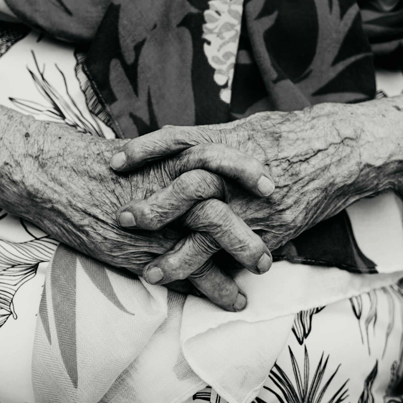 Close-up of an elderly woman’s hands resting together in her lap.